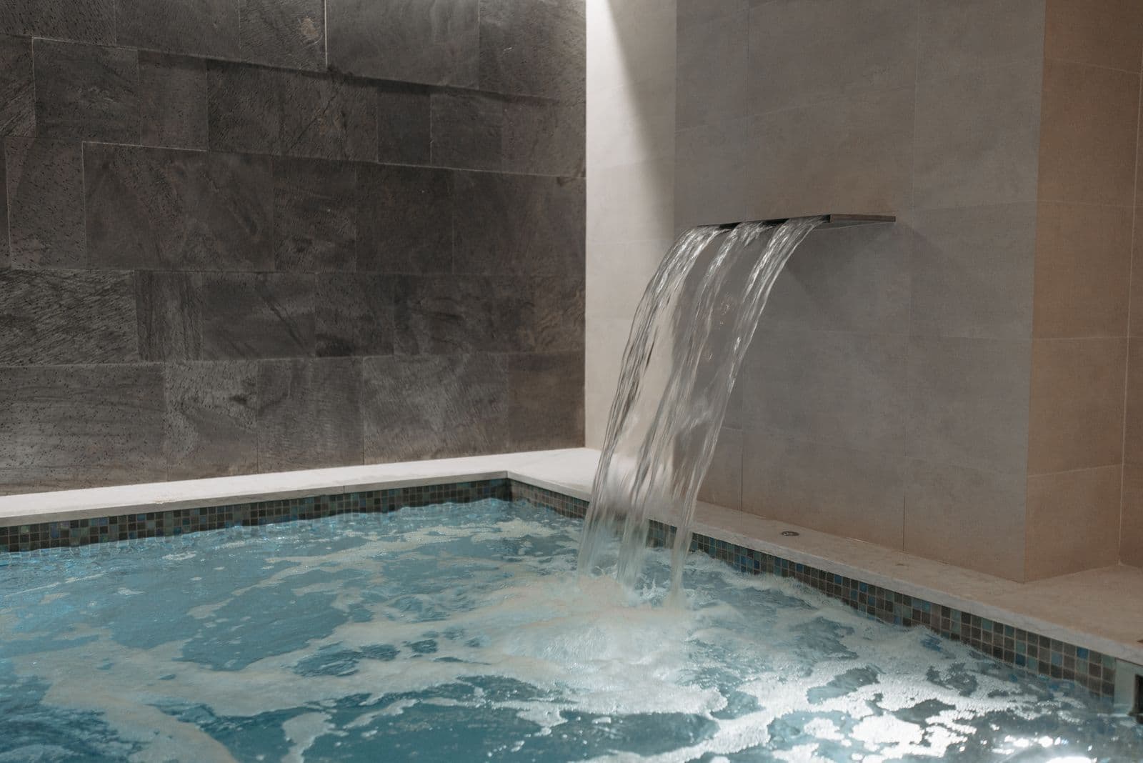 Ruhiges Thermal-Innenbecken mit Wasserfall in einem Kurbad